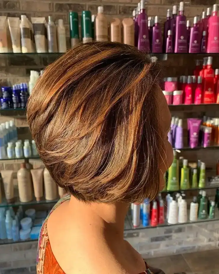 Short bob hairstyle with highlights, displayed in a salon with various hair products in the background.