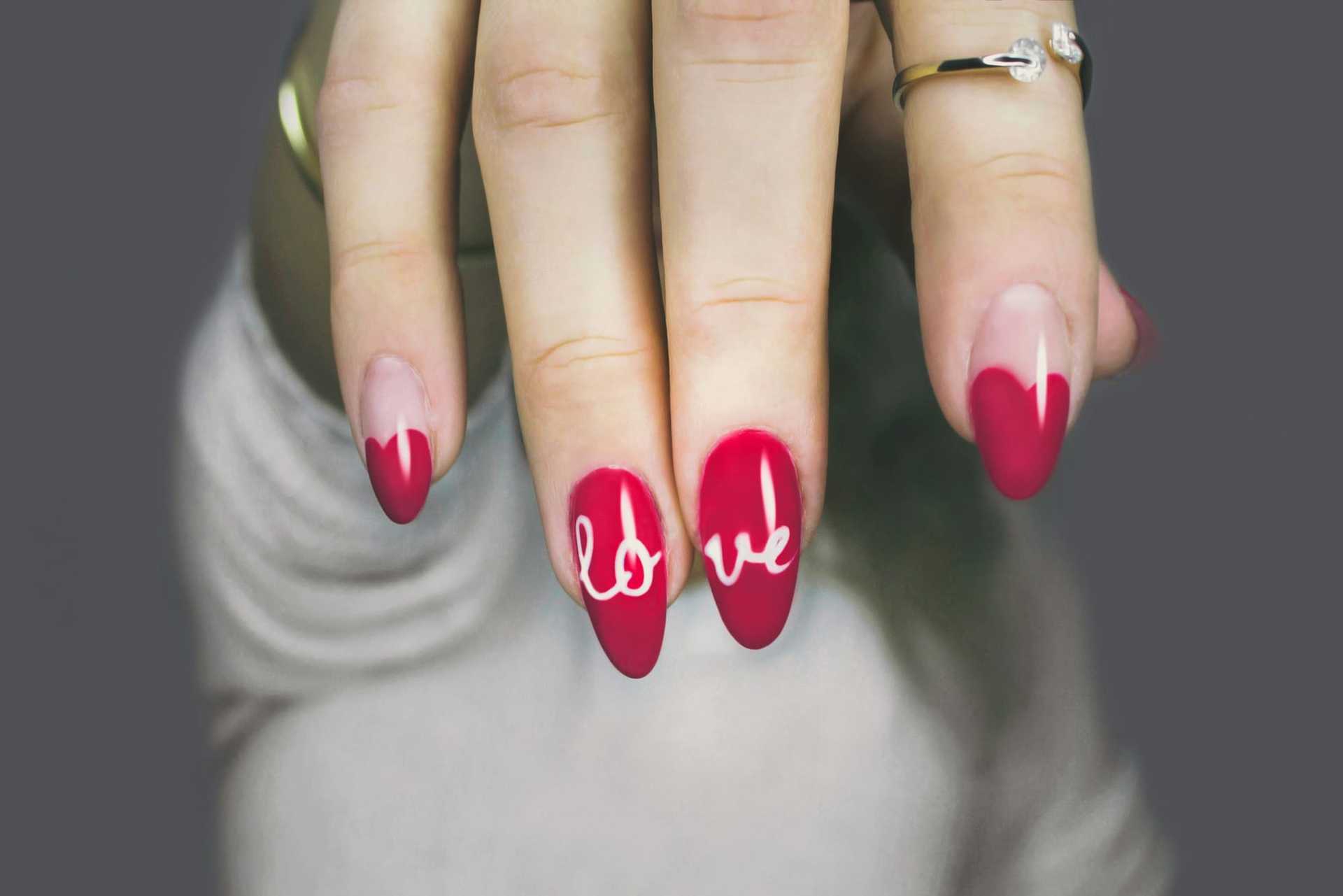 Red nails with "love" design on fingertips.