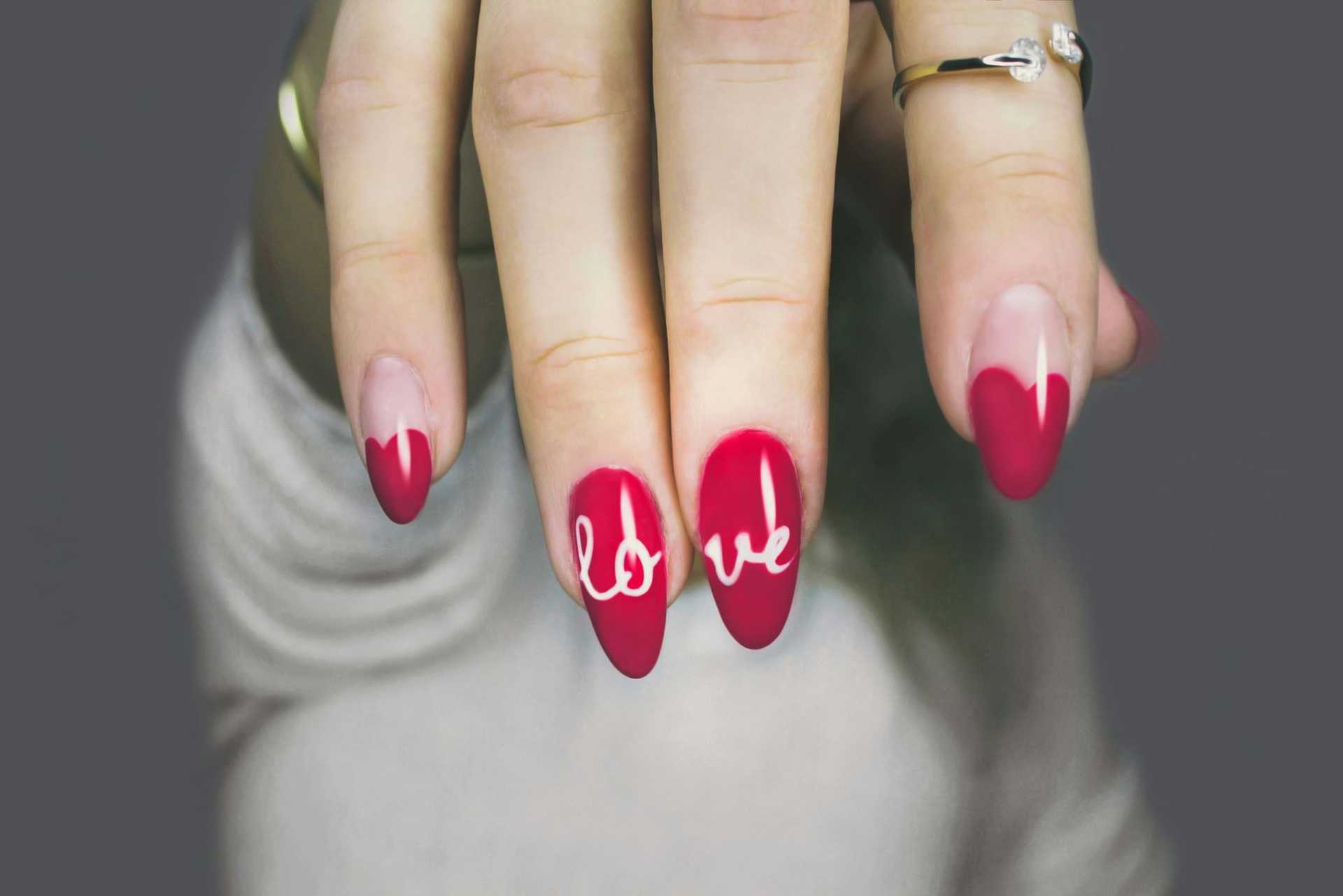 Red nails with "love" design on fingertips.