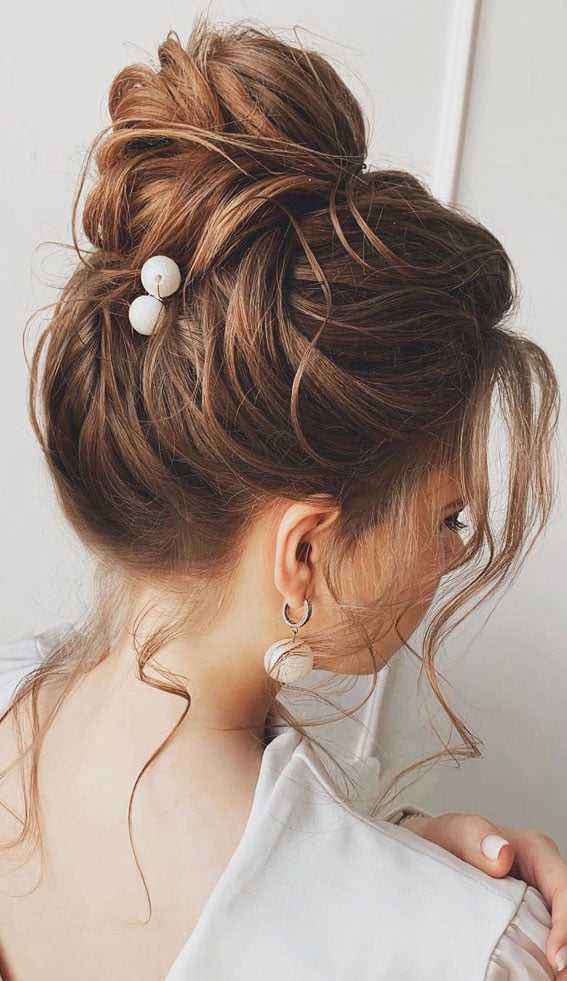 Stylish updo with decorative hairpins and loose curls, worn by a woman with brown hair.